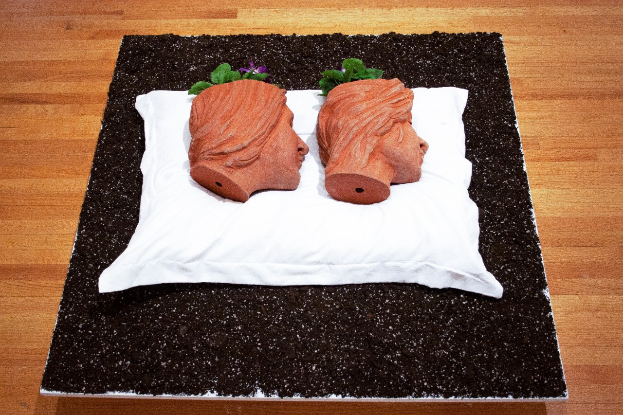 two ceramic heads on pillow with flowers