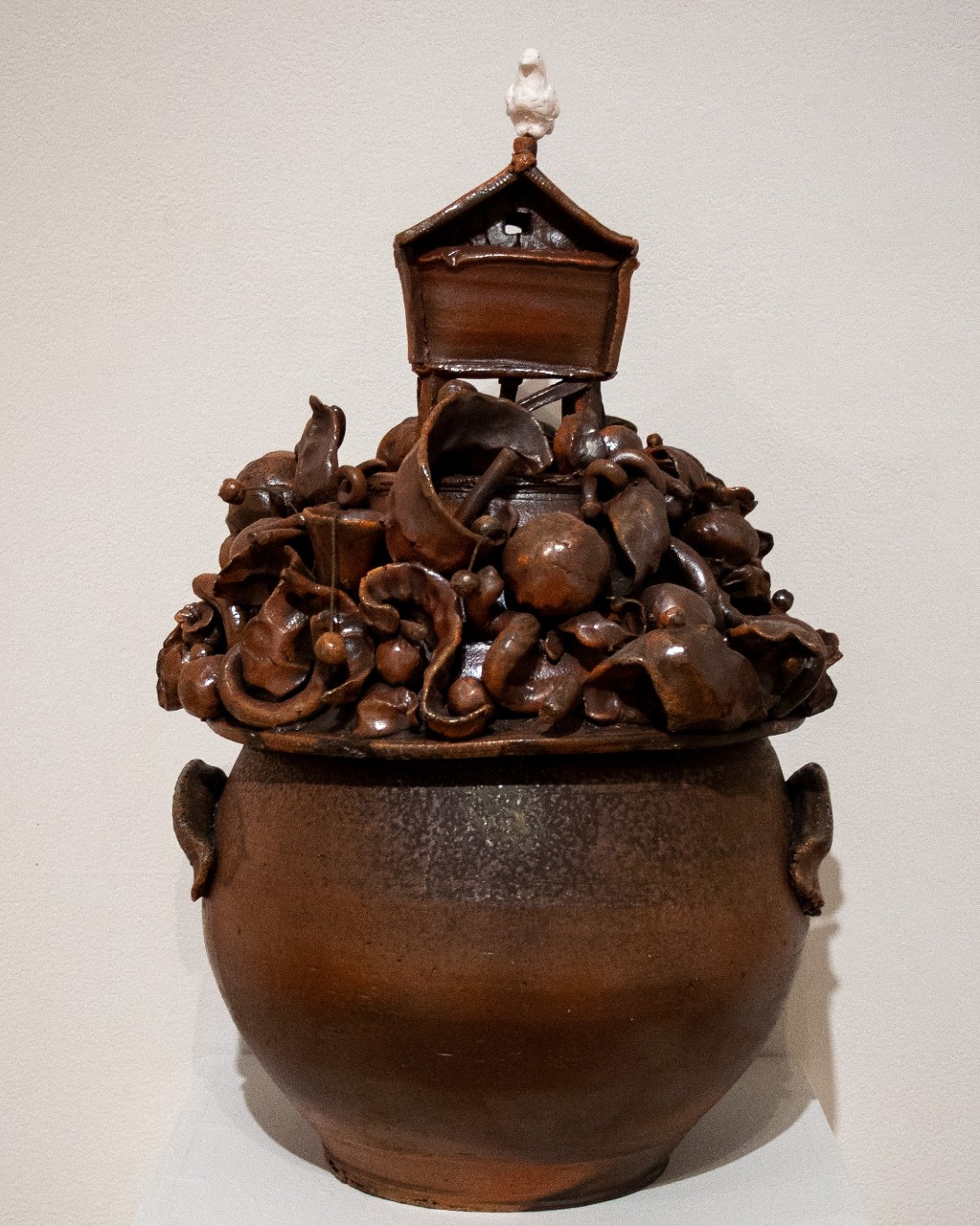 ceramic house with bird over roiling scene in vase