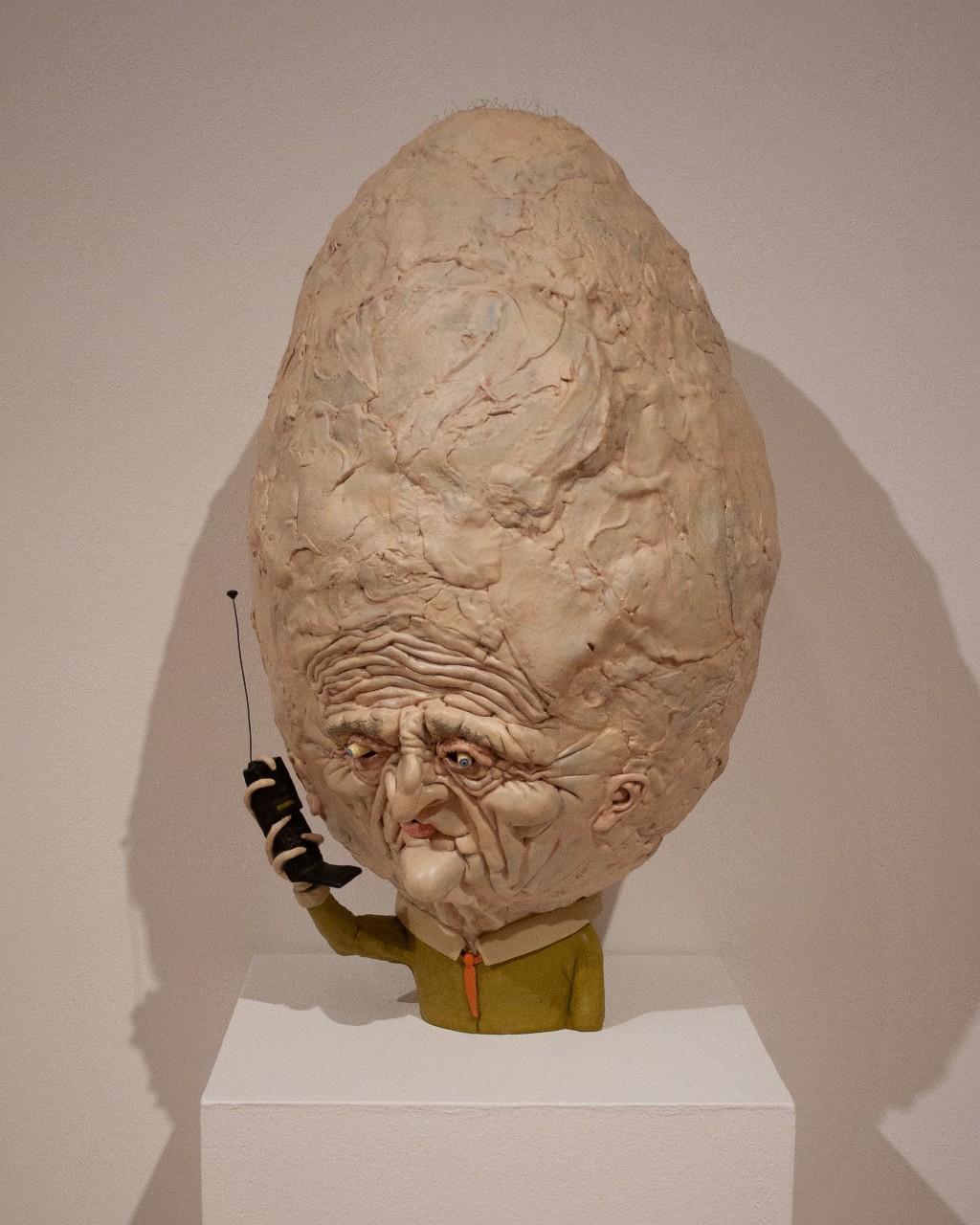 big headed sculpture with cellphone