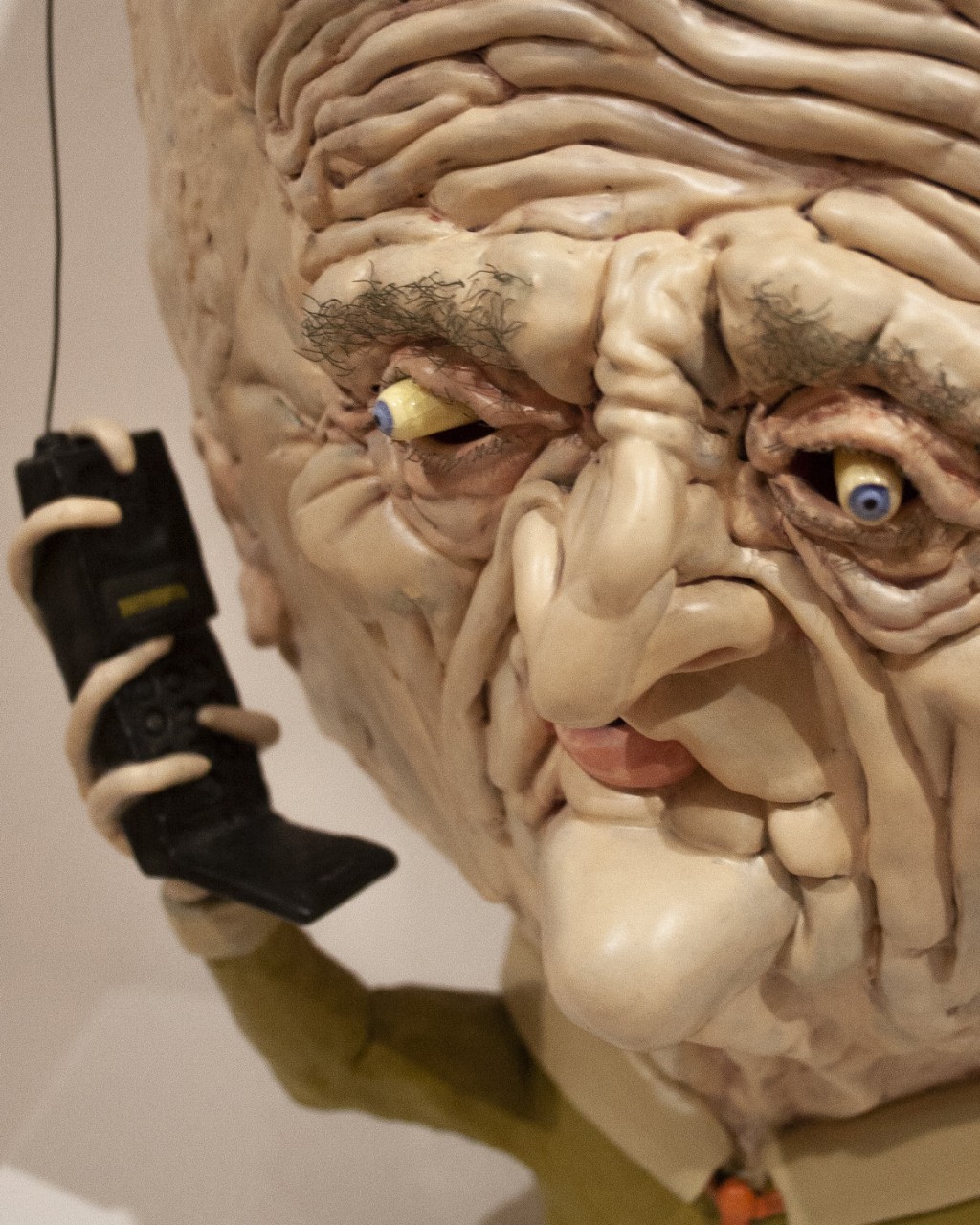 detail of big headed sculpture with cellphone