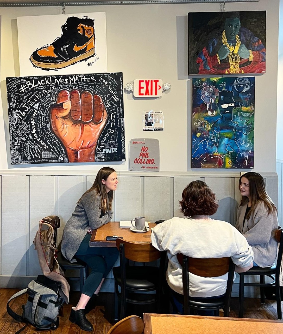 Three students chatting at a table inside the 86 coffee bar. 