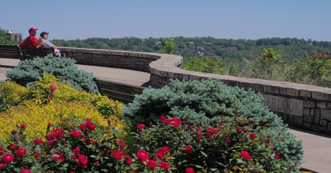 two people sit on a bench at the park overlooking the great views. 